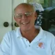 Smiling older man wearing glasses and white polo