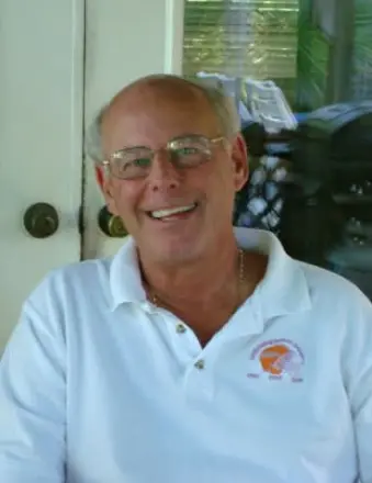 Smiling older man wearing glasses and white polo