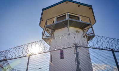 Prison guard tower behind barbed wire fence