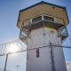 Prison guard tower behind barbed wire fence