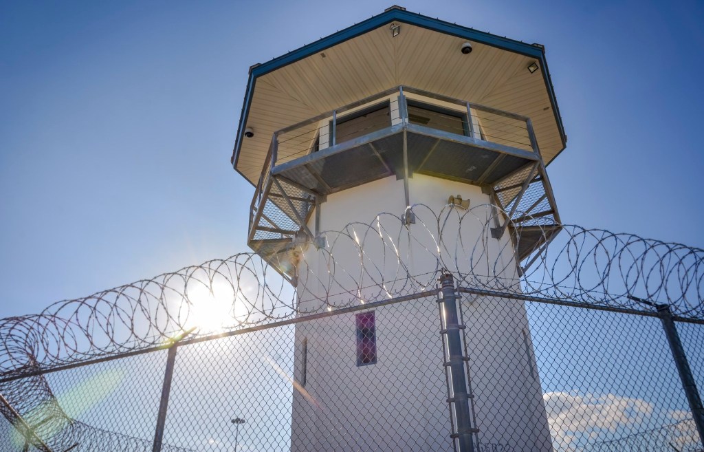 Prison guard tower behind barbed wire fence
