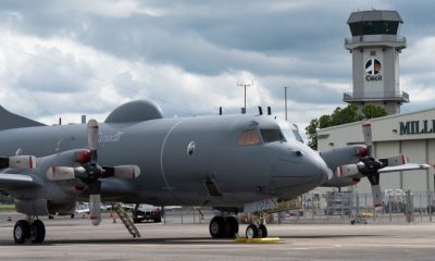 Military turboprop aircraft parked near airport hangar
