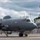 Military turboprop aircraft parked near airport hangar