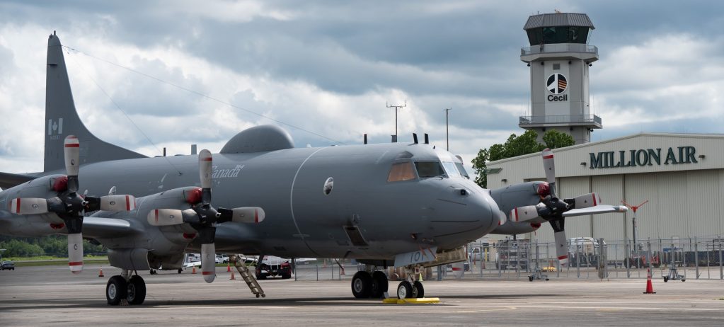 Military turboprop aircraft parked near airport hangar