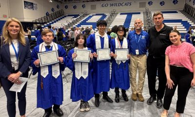 Graduates holding certificates in school gymnasium