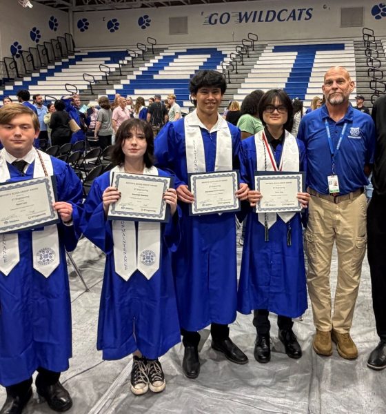 Graduates holding certificates in school gymnasium