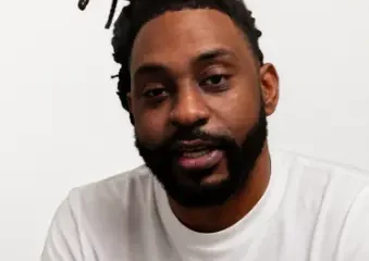 Man with dreadlocks and beard wearing white shirt