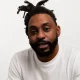 Man with dreadlocks and beard wearing white shirt