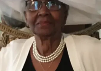 Elderly woman wearing white hat and pearl necklace