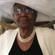 Elderly woman wearing white hat and pearl necklace