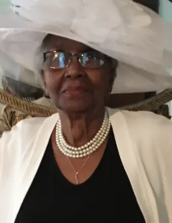 Elderly woman wearing white hat and pearl necklace
