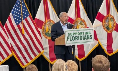 Man speaking at podium with Florida flags