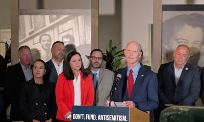 Man speaking at podium with antisemitism sign