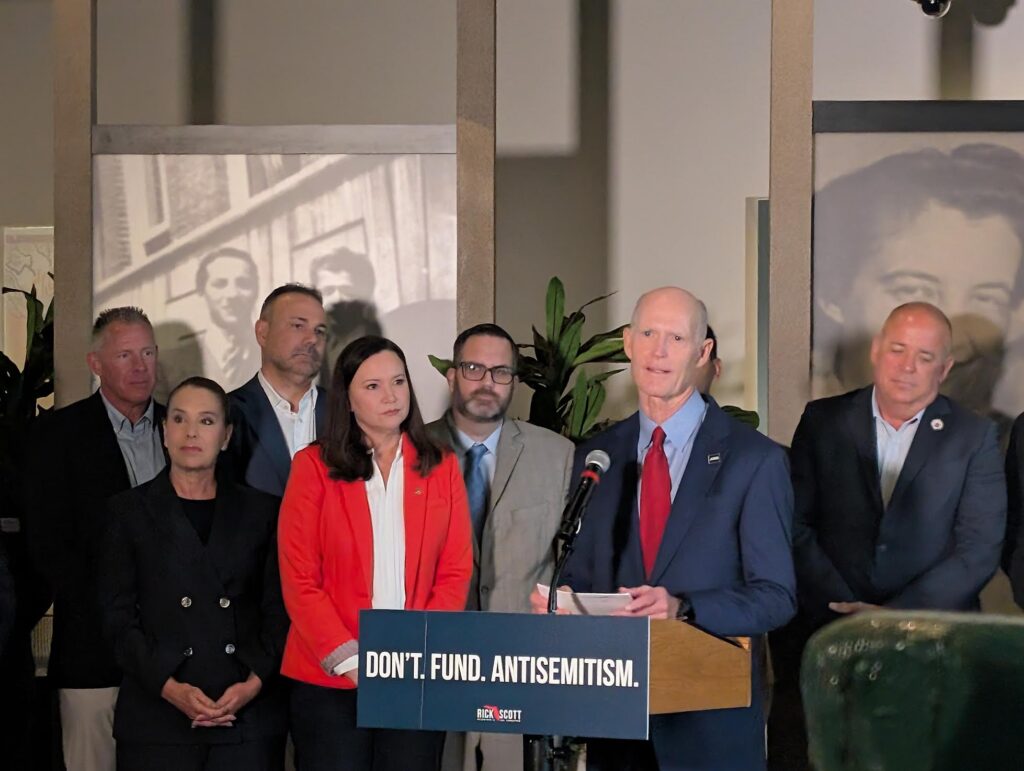 Man speaking at podium with antisemitism sign