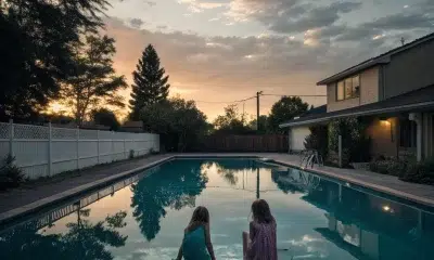 Two children sitting by backyard pool at sunset