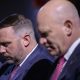 Two suited men with heads bowed solemnly