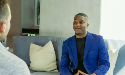 Man in blue blazer talking on couch