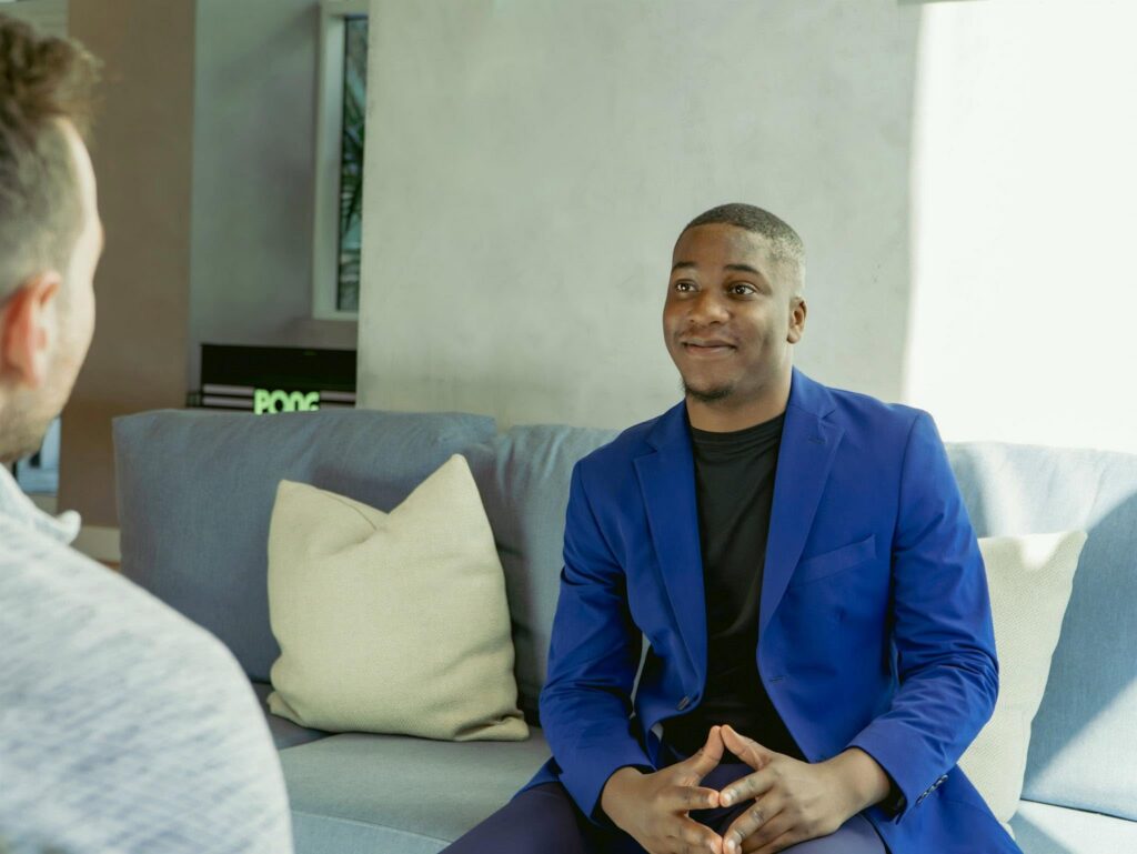 Man in blue blazer talking on couch