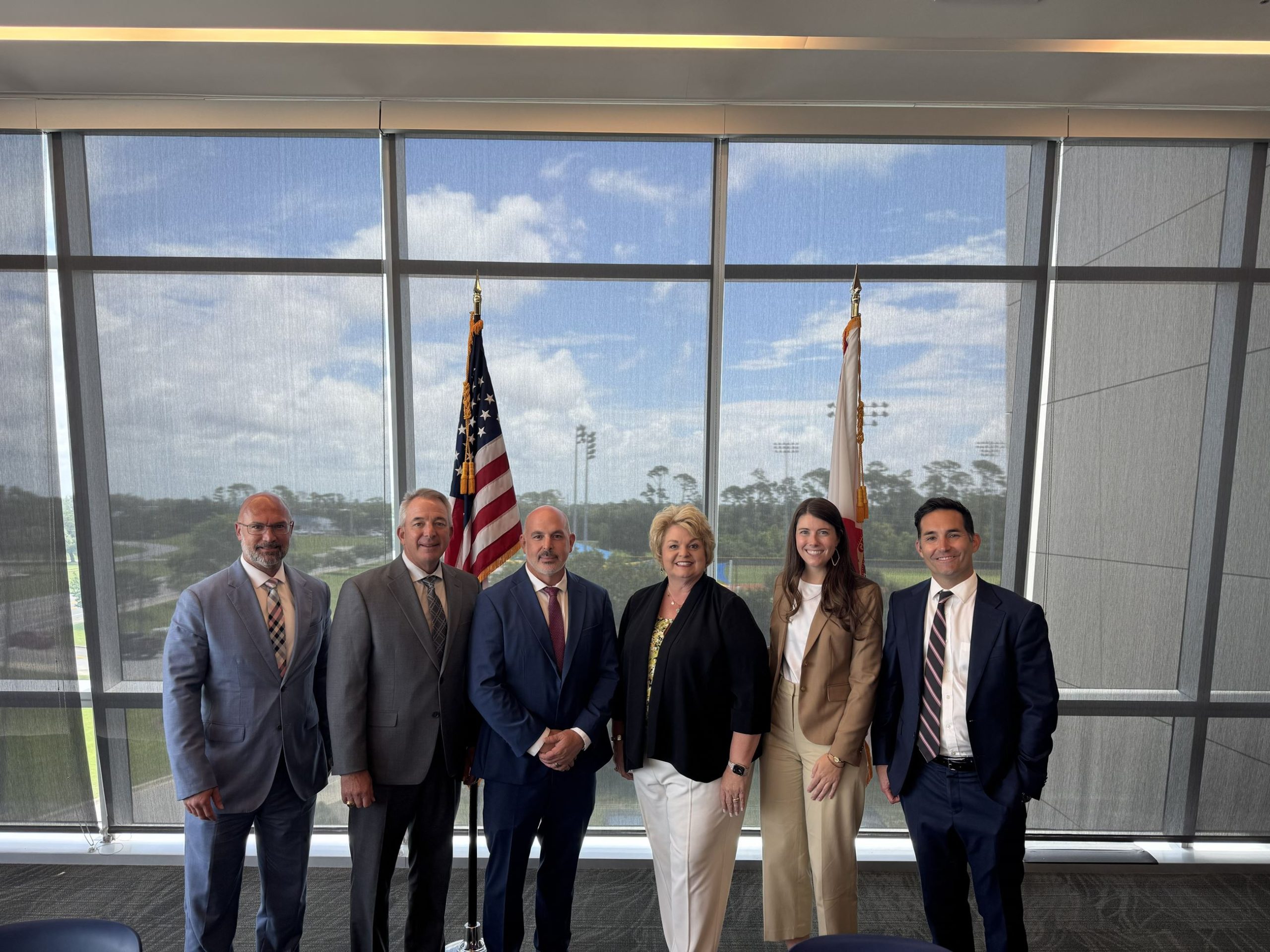 Six professionals posing indoors with American flag.