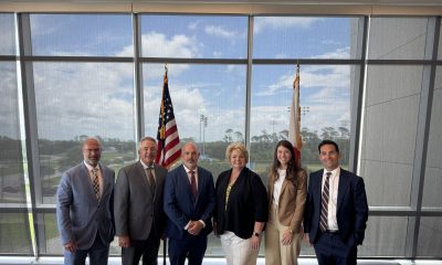 Six professionals standing before U.S. and state flags