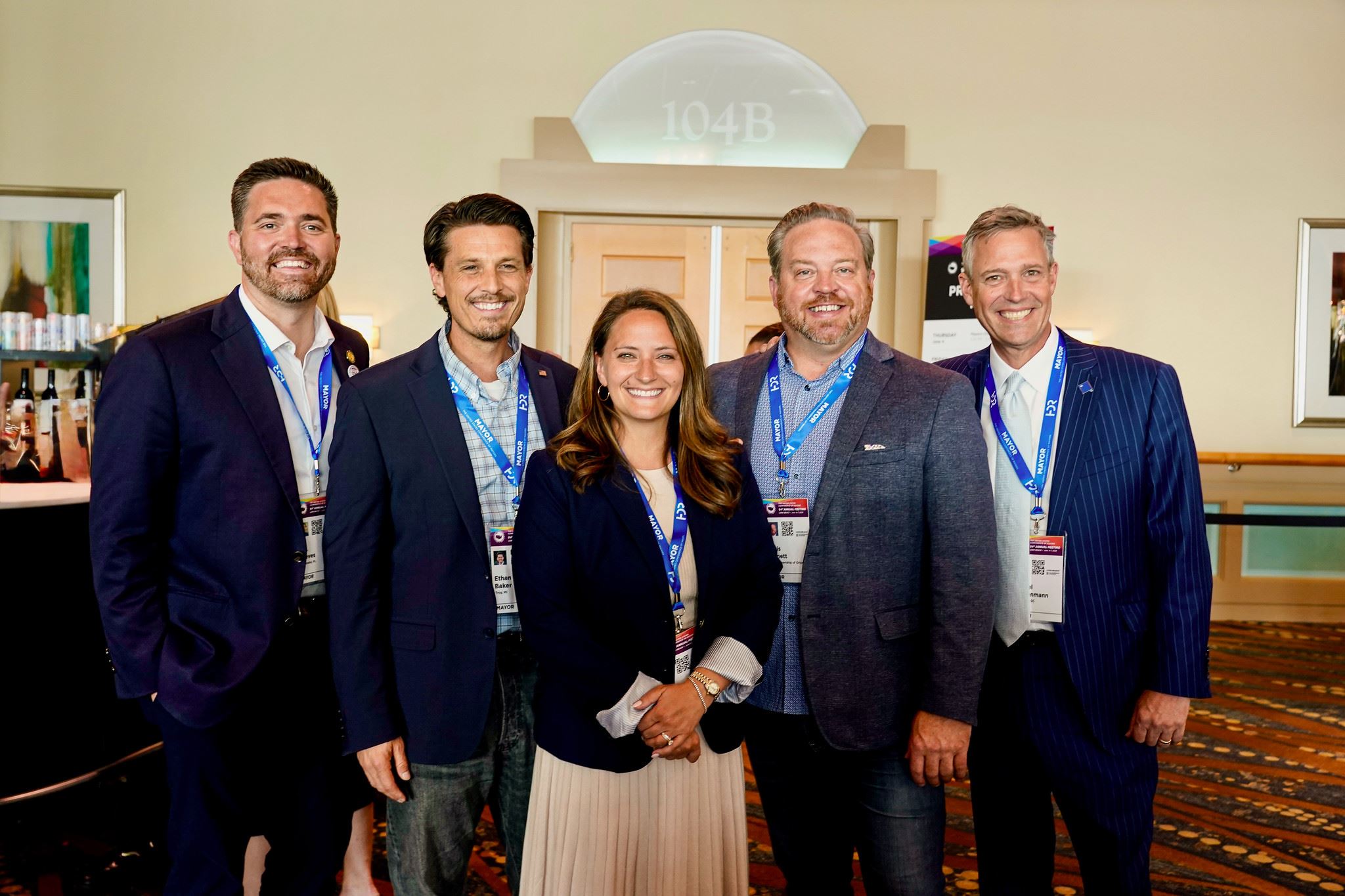 Five professionals posing at conference event indoors