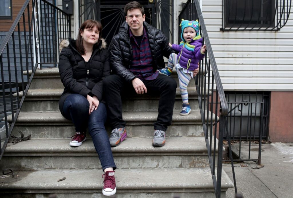 Family sitting on urban stoop with toddler