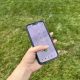 Hand dialing 911 on smartphone outdoors