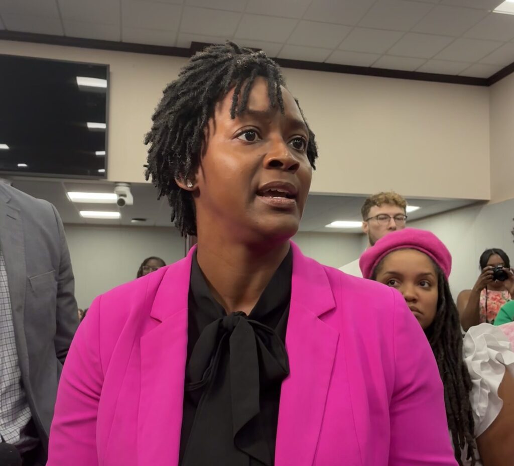 Woman in pink blazer speaking indoors