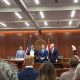 Officials holding signed document in government chamber