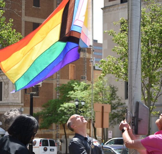 People raising rainbow Pride flag in city