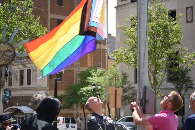 People raising rainbow Pride flag in city