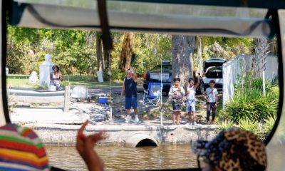Family waving from shore to passing boat