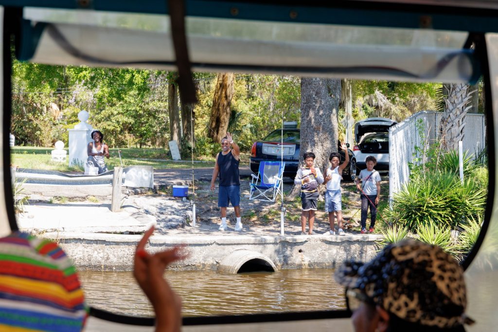 Family waving from shore to passing boat