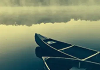 Two canoes on a misty calm lake