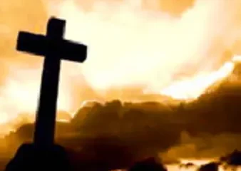 Silhouette of cross against dramatic golden sunset sky