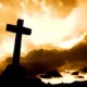 Silhouette of cross against dramatic golden sunset sky