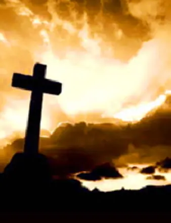 Silhouette of cross against dramatic golden sunset sky