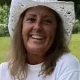 Smiling woman in white cowboy hat holding small white puppy