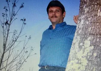 Man leaning against tree at dusk outdoors