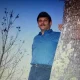 Man leaning against tree at dusk outdoors