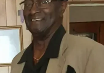 Smiling man in tan blazer and black cap