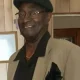 Smiling man in tan blazer and black cap