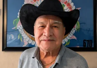 Older man in black cowboy hat indoors