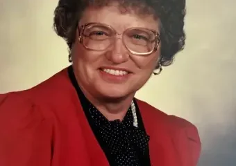 Woman with curly hair wearing red blazer and glasses