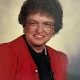 Woman with curly hair wearing red blazer and glasses