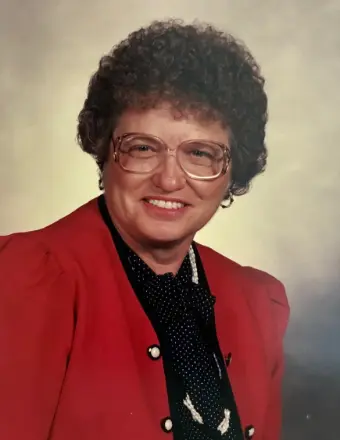 Woman with curly hair wearing red blazer and glasses