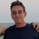 Man smiling by the ocean at sunset