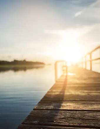 Wooden dock at sunrise over calm lake