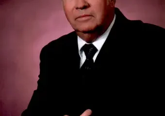 Older man in suit against pink backdrop