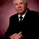 Older man in suit against pink backdrop